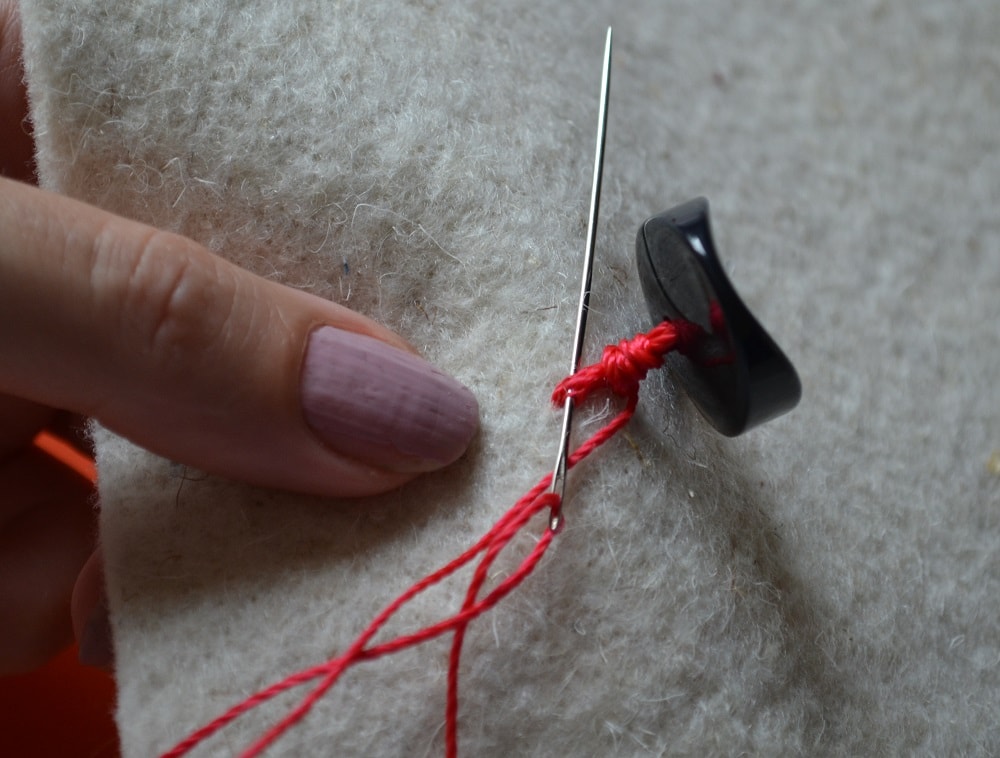 Insert the needle tip at the base of leg a button