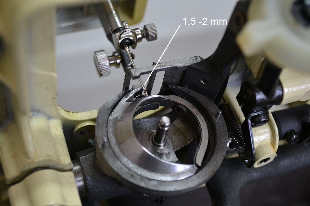The tip of the shuttle hook should pass above the eye of the needle