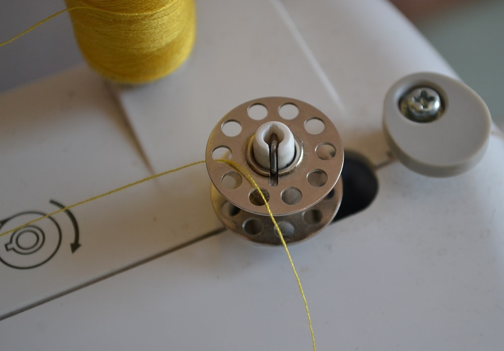 Pass the thread end into hole a bobbin