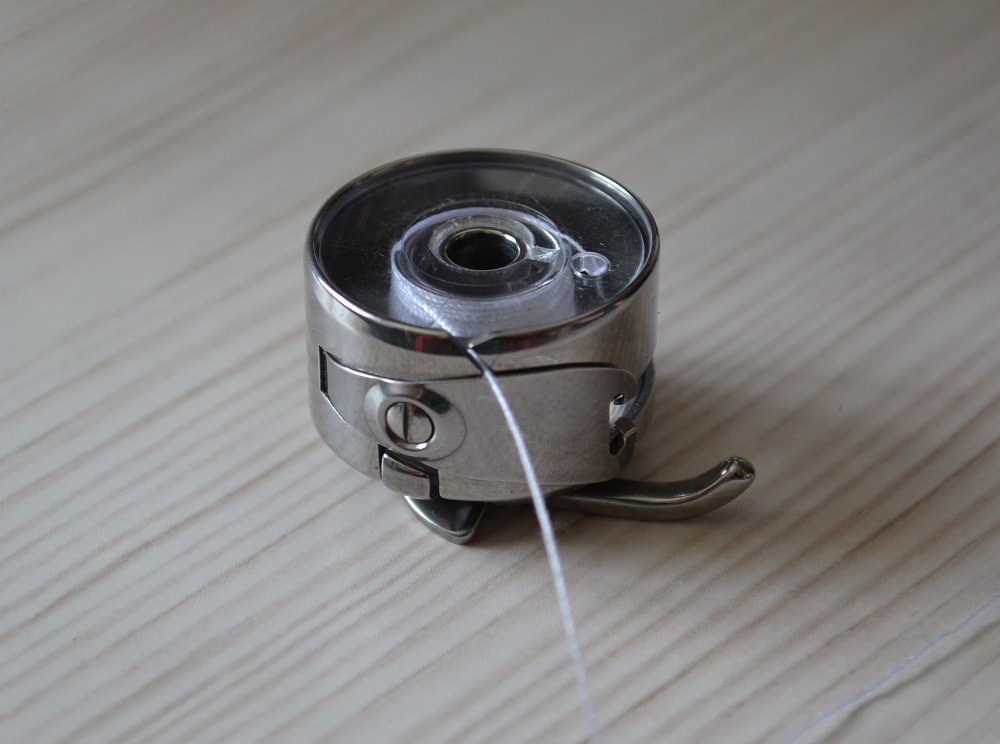 Pass thread end through the slit